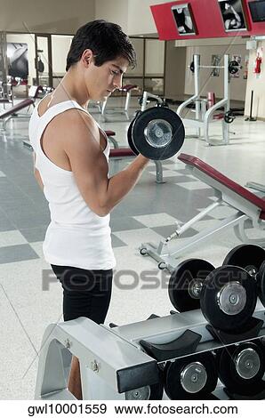 Man exercising with dumbbells in a gym View Large Photo Image Stock Photo - Man exercising with dumbbells in a gym. Fotosearch