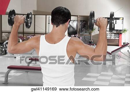 Man exercising with dumbbells in a gym View Large Photo Image Stock Photo - Man exercising with dumbbells in a gym. Fotosearch