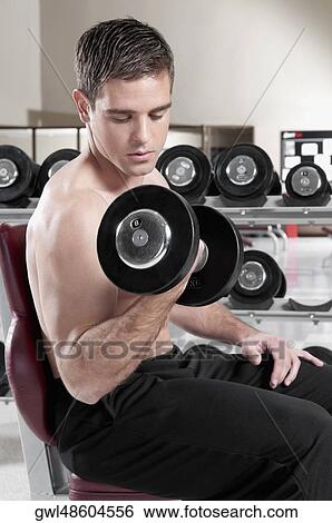 Man exercising with dumbbells in a gym View Large Photo Image Stock Photograph - Man exercising with dumbbells in a gym. Fotosearch