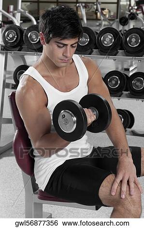 Man exercising with dumbbells in a gym View Large Photo Image Stock Photograph - Man exercising with dumbbells in a gym. Fotosearch