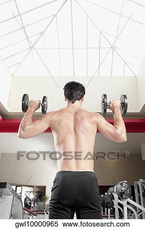 Man exercising with dumbbells in a gym View Large Photo Image Stock Photography - Man exercising with dumbbells in a gym. Fotosearch
