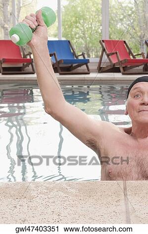 Stock Image - Man exercising with dumbbells in a swimming pool. Fotosearch