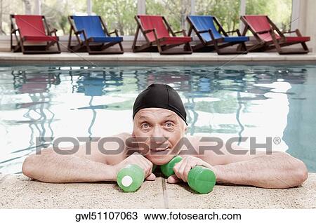 Stock Image - Man exercising with dumbbells in a swimming pool. Fotosearch