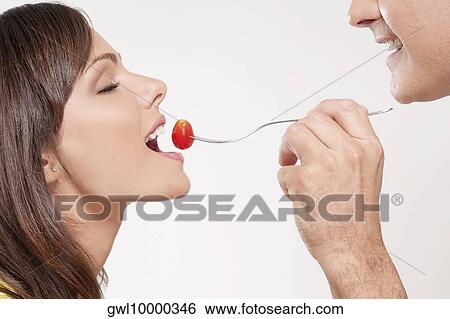 Man feeding woman a cherry tomato View Large Photo Image Stock Photograph - Man feeding woman a cherry tomato. Fotosearch