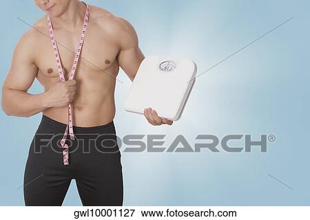 Man holding a bathroom scale View Large Photo Image Stock Photo - Man holding a bathroom scale. Fotosearch