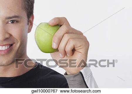 Stock Photo - Man holding a green apple. Fotosearch