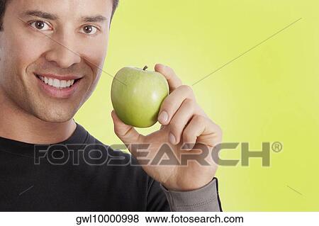 Stock Photo - Man holding a green apple. Fotosearch