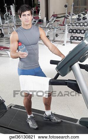 Man holding a water bottle on a treadmill View Large Photo Image Stock Image - Man holding a water bottle on a treadmill. Fotosearch