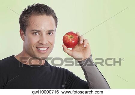 Man holding an apple View Large Photo Image Stock Photograph - Man holding an apple. Fotosearch