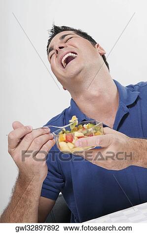 Man laughing while eating fruit salad View Large Photo Image Stock Image - Man laughing while eating fruit salad. Fotosearch