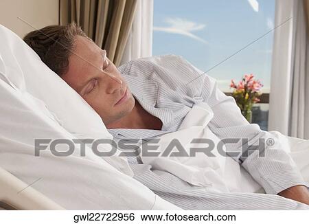 Stock Photograph - Man lying in a hospital bed. Fotosearch