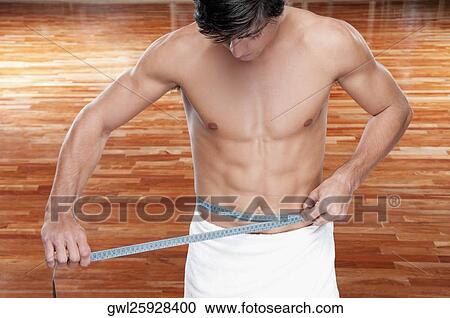 Man measuring his waist with a tape measure View Large Photo Image Stock Image - Man measuring his waist with a tape measure. Fotosearch
