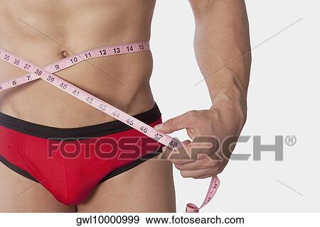 Stock Photo - Man measuring his waist with a tape measure. Fotosearch