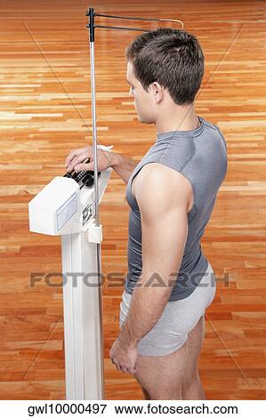 Man measuring his weight on a weighing scale View Large Photo Image Stock Photo - Man measuring his weight on a weighing scale. Fotosearch