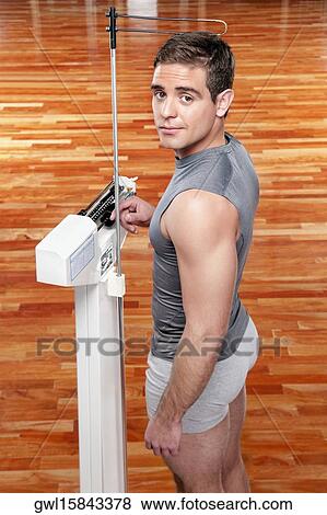 Man measuring his weight on a weighing scale View Large Photo Image Stock Photo - Man measuring his weight on a weighing scale. Fotosearch