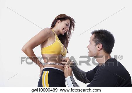 Man measuring the waist of a woman with a tape measure View Large Photo Image Stock Photo - Man measuring the waist of a woman with a tape measure. Fotosearch