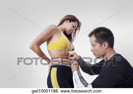 Man measuring the waist of a woman with a tape measure View Large Photo Image Stock Photo - Man measuring the waist of a woman with a tape measure. Fotosearch