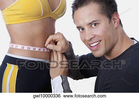 Man measuring the waist of a woman with a tape measure View Large Photo Image Stock Photograph - Man measuring the waist of a woman with a tape measure. Fotosearch