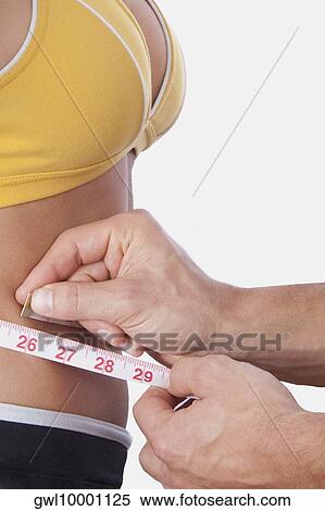 Man measuring the waist of a woman with a tape measure View Large Photo Image Stock Photography - Man measuring the waist of a woman with a tape measure. Fotosearch