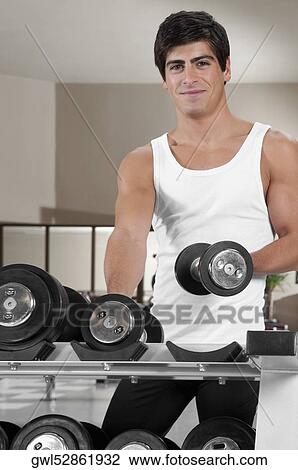 Man picking up a dumbbell in a gym View Large Photo Image Stock Image - Man picking up a dumbbell in a gym. Fotosearch