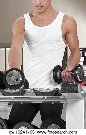 Man picking up dumbbells in a gym View Large Photo Image Stock Image - Man picking up dumbbells in a gym. Fotosearch