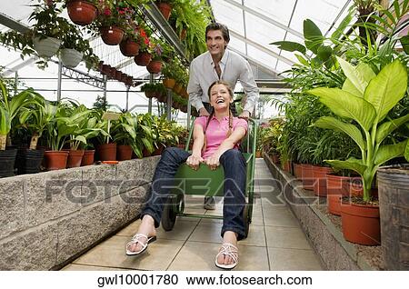 Man pushing a woman sitting on a push cart in a greenhouse View Large Photo Image Stock Image - Man pushing a woman sitting on a push cart in a greenhouse. Fotosearch