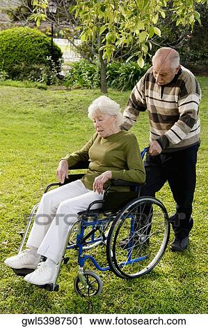 Man pushing his disabled wife's wheelchair in a garden View Large Photo Image Stock Image - Man pushing his disabled wife's wheelchair in a garden. Fotosearch