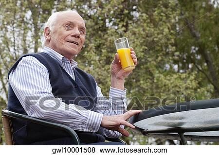 Man sitting on a chair and drinking juice View Large Photo Image Stock Photo - Man sitting on a chair and drinking juice. Fotosearch