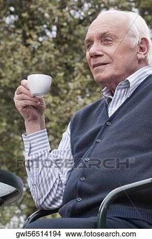 Man sitting on a chair and drinking tea View Large Photo Image Picture - Man sitting on a chair and drinking tea. Fotosearch