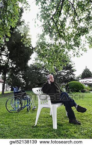 Man sitting on a chair and talking on a mobile phone View Large Photo Image Stock Photo - Man sitting on a chair and talking on a mobile phone. Fotosearch