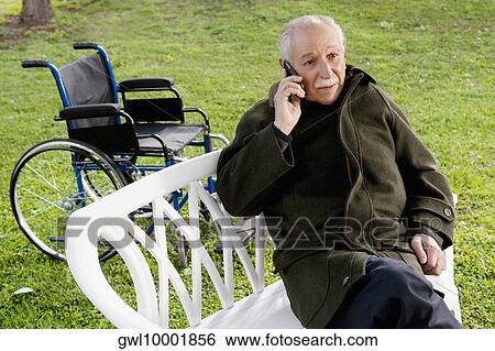 Man sitting on a chair and talking on a mobile phone View Large Photo Image Stock Photograph - Man sitting on a chair and talking on a mobile phone. Fotosearch