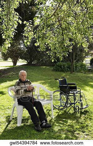Man sitting on a chair in a park View Large Photo Image Picture - Man sitting on a chair in a park. Fotosearch