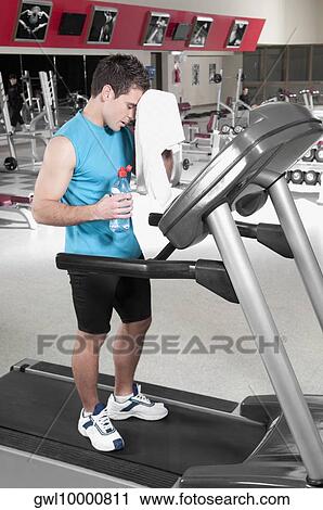 Man wiping his face with a towel on a treadmill View Large Photo Image Stock Image - Man wiping his face with a towel on a treadmill. Fotosearch