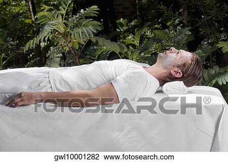 Stock Image - Man with facial mask lying on a massage table. Fotosearch