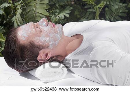 Man with facial mask lying on a massage table View Large Photo Image Stock Photo - Man with facial mask lying on a massage table. Fotosearch