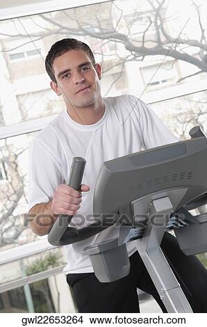 Man working out on an exercise bike in a gym View Large Photo Image Picture - Man working out on an exercise bike in a gym. Fotosearch