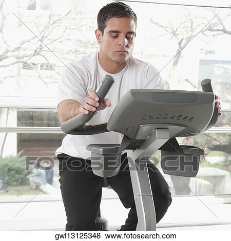 Man working out on an exercise bike in a gym View Large Photo Image Stock Photo - Man working out on an exercise bike in a gym. Fotosearch