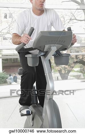 Man working out on an exercise bike in a gym View Large Photo Image Stock Photograph - Man working out on an exercise bike in a gym. Fotosearch