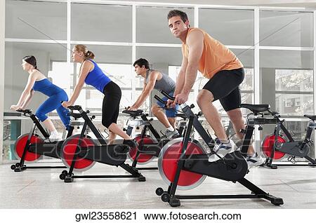 Men and women working out on exercise bikes in a gym View Large Photo Image Stock Image - Men and women working out on exercise bikes in a gym. Fotosearch