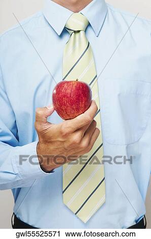 Mid section view of a businessman holding a red apple View Large Photo Image Stock Image - Mid section view of a businessman holding a red apple. Fotosearch