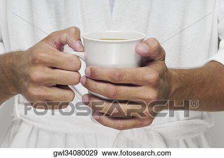 Mid section view of a man holding a cup of coffee View Large Photo Image Stock Photo - Mid section view of a man holding a cup of coffee. Fotosearch
