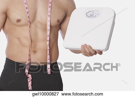 Mid section view of a man holding a bathroom scale View Large Photo Image Stock Photo - Mid section view of a man holding a bathroom scale. Fotosearch