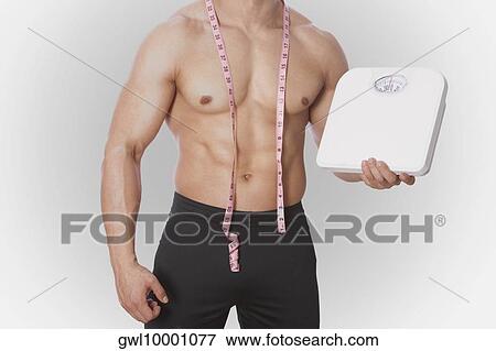 Mid section view of a man holding a bathroom scale View Large Photo Image Stock Photo - Mid section view of a man holding a bathroom scale. Fotosearch