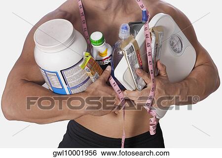 Mid section view of a man holding food supplements and a bathroom scale View Large Photo Image Stock Photograph - Mid section view of a man holding food supplements and a bathroom scale. Fotosearch
