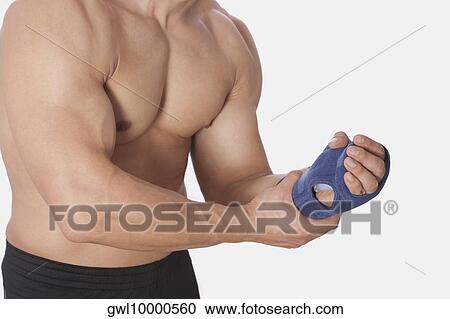 Stock Image - Mid section view of a man holding his wrist. Fotosearch