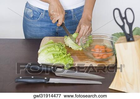 Mid section view of a woman chopping lettuce View Large Photo Image Stock Photo - Mid section view of a woman chopping lettuce. Fotosearch