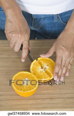 Picture - Mid section view of a woman cutting an orange. Fotosearch