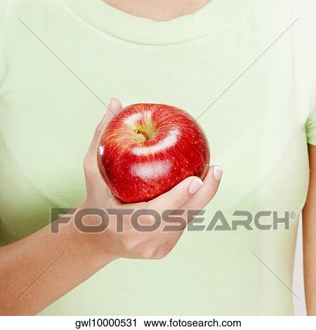 Mid section view of a woman holding a red apple View Large Photo Image Stock Image - Mid section view of a woman holding a red apple. Fotosearch