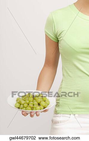 Mid section view of a woman holding a bowl of grapes View Large Photo Image Stock Image - Mid section view of a woman holding a bowl of grapes. Fotosearch
