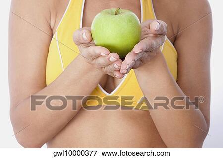 Mid section view of a woman holding a green apple View Large Photo Image Stock Photo - Mid section view of a woman holding a green apple. Fotosearch